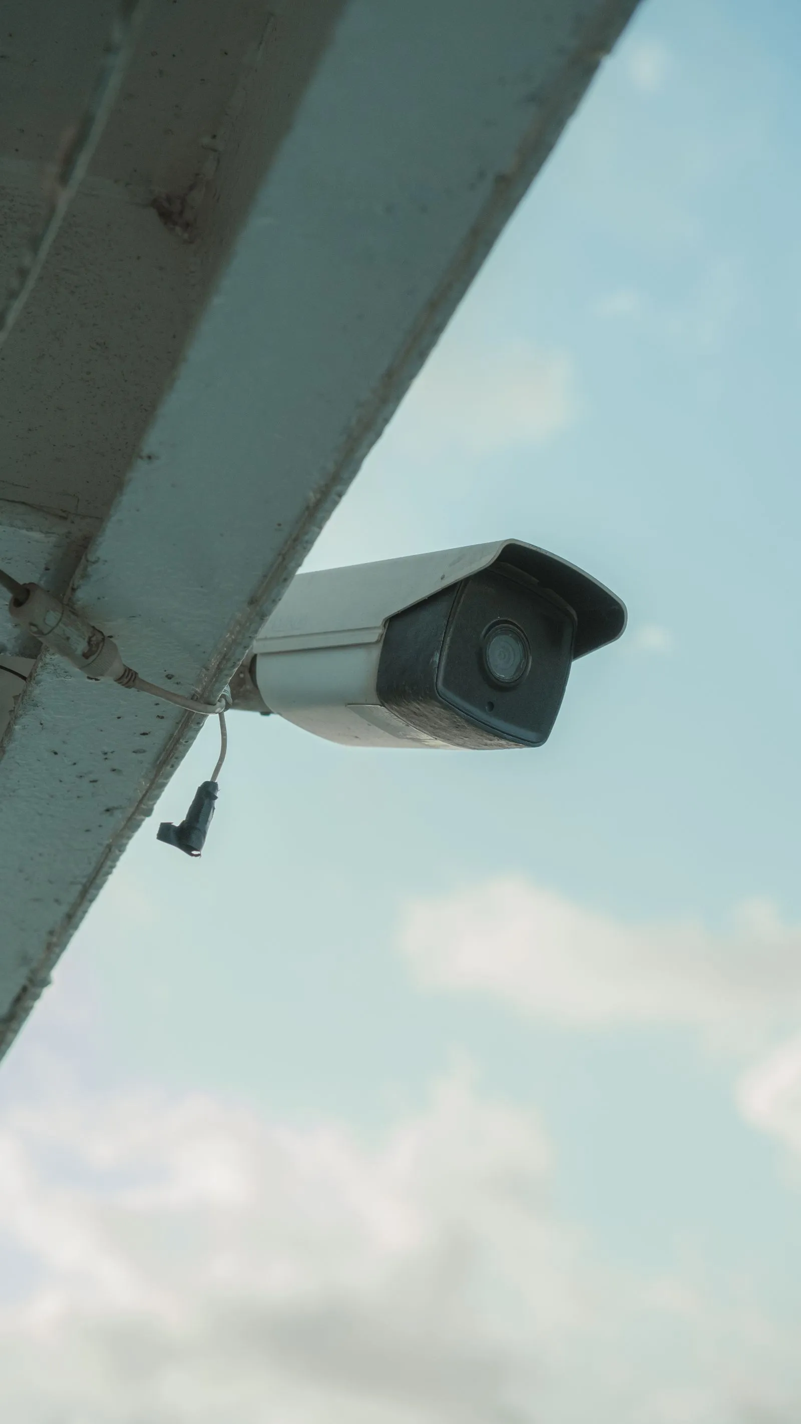 A bullet security camera mounted under the eaves of a house