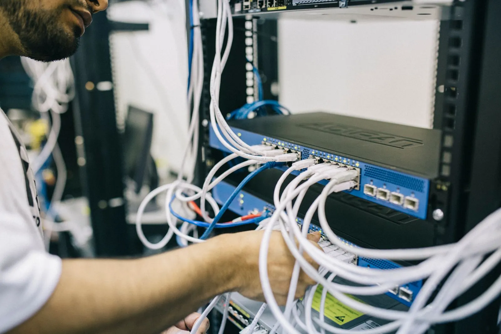 Hands connecting network cables to a switch in a rack
