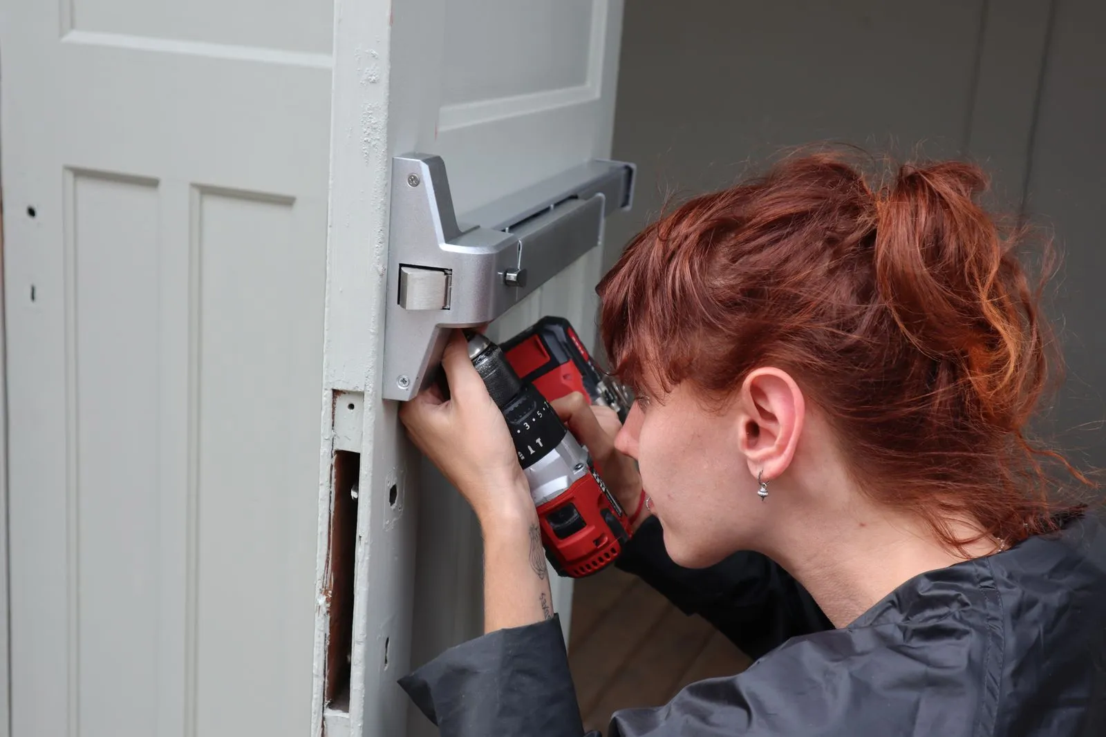 A tradesperson drilling at the frame of a front door
