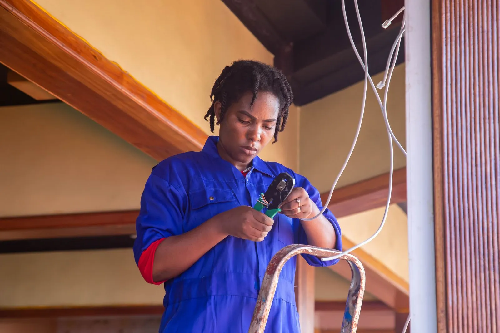 A technician in overalls stripping a cable indoors